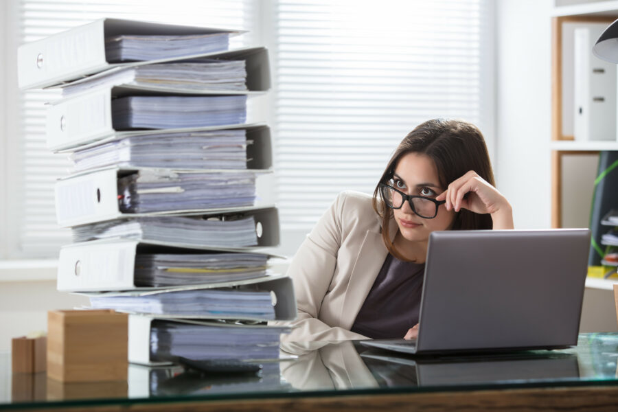 Worried businesswoman looking at folders stack